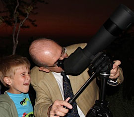 El astrónomo José Maza, le enseña a un niño a observar el planeta Júpiter a través del telescopio.